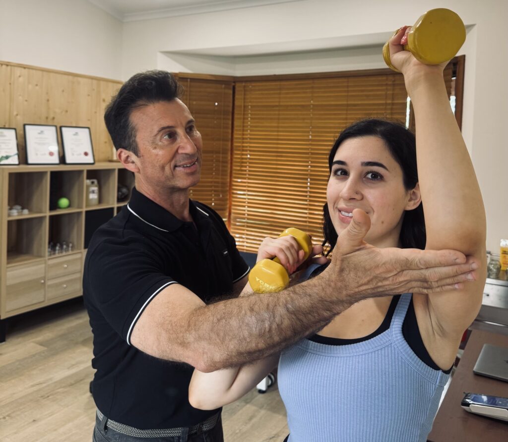 Myotherapist assessing a client's shoulder movement at Mi Therapy Clinic
