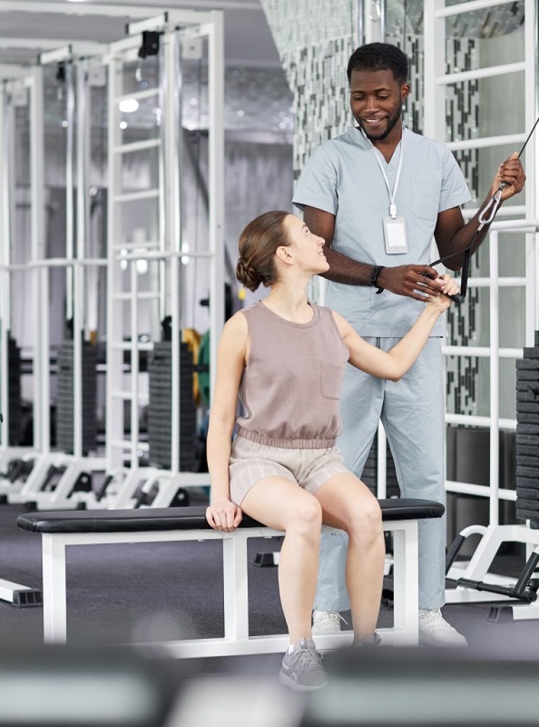 Portrait of smiling therapist assisting female patient in rehabilitation clinic, copy space